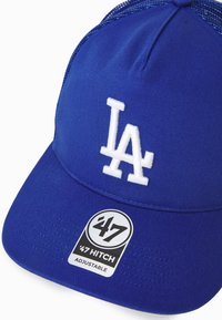 Căciulă de baseball albastră cu un design din material solid, logo alb "LA" și spate din plasă. Dispune de o curea ajustabilă și un etichetă logo pe margine.