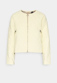 Veste matelassée jaune pâle avec un col rond, une fermeture éclair et deux poches latérales ornées de ferrures métalliques. Coupe courte.