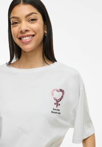 Witte katoenen t-shirt met een ronde halslijn, voorzien van een pailletten roze hart en een vrouwelijk symbool ontwerp, vergezeld van de tekst "Elke dag is Vrouwendag."