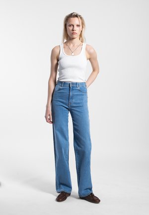 Vaaleansiniset korkeavyötäröiset farkut, suoranlahkeiset ja hieman löysät. Yhdistetty valkoiseen ribattuun tanktoppiin ja ruskeisiin nauhakenkiin.