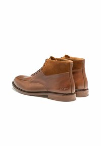 Bottines en cuir brun avec une finition lisse, des accents en daim, un bout arrondi et un design à lacets, dotées d'une semelle en caoutchouc durable.