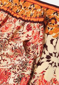 Tkanina w kwiatowy wzór w kolorach kremowym, czerwonym i pomarańczowym. Zgromadzony pas w brązowym wykończeniu. Miękka faktura z bogatymi detalami wzorniczymi.