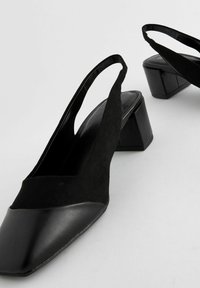 Mustat slingback-korkokengät, joissa on kärjellinen muoto, yhdistelmä sileää nahkaa ja samettimateriaaleja, sekä paksu korko.