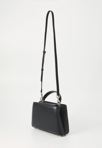 Sac à main en cuir noir avec une forme structurée, une courte anse supérieure et une sangle longue réglable. Doté de quincaillerie en métal et d'un fond plat.