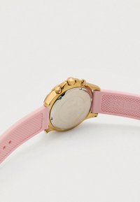 Sat zlatne boje s ružičastim silikonskim remenom. Okruglo kućište, tri tipke za pritiskanje, teksturirani remen i ugravirani stražnji poklopac kućišta.