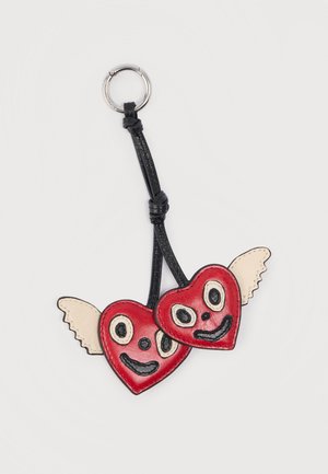 Deux cœurs en cuir rouge avec des visages cousus et des ailes beige attachés à une sangle en cuir noir et un porte-clés en argent.