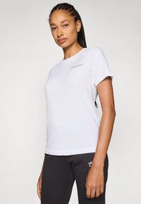 Witte katoenen t-shirt met korte mouwen, met een subtiele geborduurde logo op de bovenste linkerkant van de borst. Soepele textuur en klassieke pasvorm.
