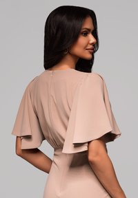 Sukienka w kolorze nude z rozszerzanymi rękawami, marszczoną talią i zapięciem na zamek z tyłu. Gładki materiał o matowym wykończeniu.