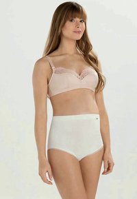 Μπεζ σουτιέν με δαντελένιες λεπτομέρειες και ρυθμιζόμενες τιράντες, σε συνδυασμό με λευκά σλιπ ψηλής μέσης που διαθέτουν λεία υφή και τόνο στη ραφή.