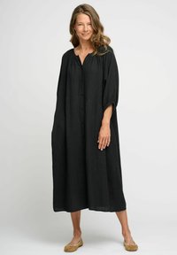 Rochie din in negru, cu o croială lejeră, cu închidere pe butoane în față și mâneci 3/4. Prezintă un guler rotund și buzunare laterale, ajungând până la jumătatea gambei.