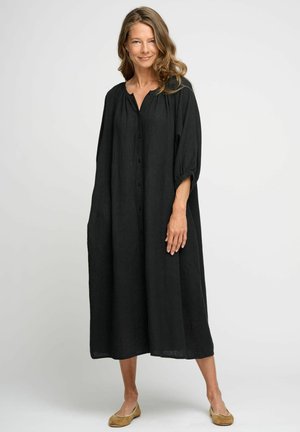 Rochie din in negru, cu o croială lejeră, cu închidere pe butoane în față și mâneci 3/4. Prezintă un guler rotund și buzunare laterale, ajungând până la jumătatea gambei.