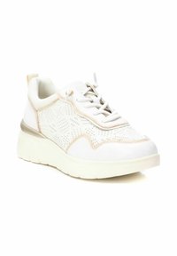 Sneaker bianca con tomaia perforata, accenti beige e una spessa suola bianca. Presenta punta arrotondata, lacci piatti e un linguetta sul tallone.