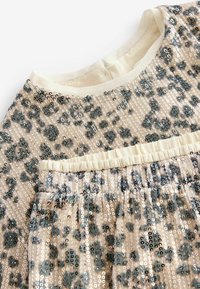 Seydressed med let beige stof, prydet med et leopardmønster i grå. Elastisk talje og blød udskæring, glat tekstur.
