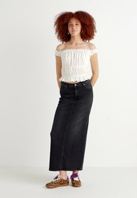 White off-the-shoulder top with ruffled edges, black denim maxi skirt, and brown leopard-print sneakers with purple accents.