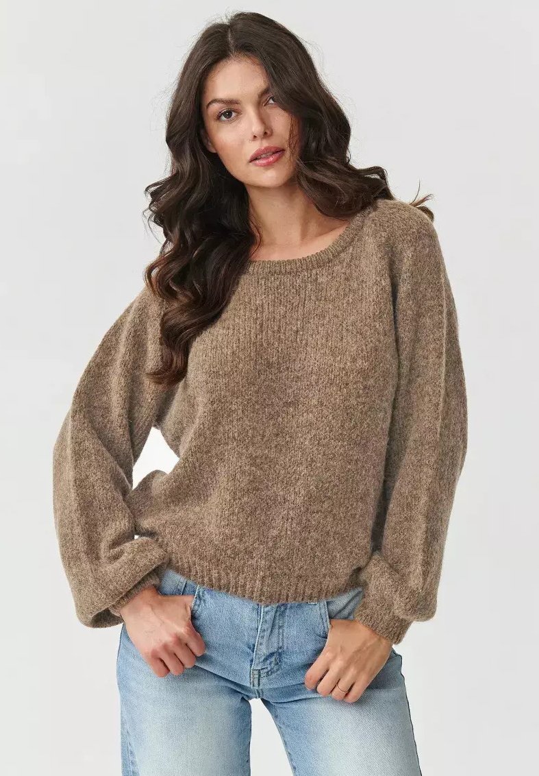 Brązowy pleciony sweter z okrągłym dekoltem, oversized rękawami i miękką fakturą, w zestawieniu z jasnoniebieskimi dżinsami.