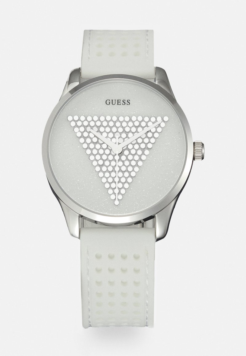 Montre-bracelet Guess blanche avec lunette argentée, triangle texturé de points sur le cadran, aiguilles blanche des heures, minutes et secondes, et un bracelet blanc perforé.