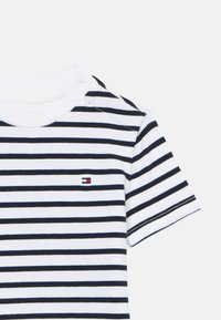 Ριγέ t-shirt με λευκές και ναυτικές οριζόντιες ρίγες, μαλακό βαμβακερό υλικό, λαιμόκοψη με κουμπιά πατιλέτας και μικρό λογότυπο στο στήθος.