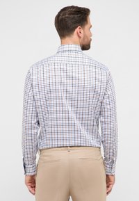 Wit overhemd met lange mouwen en knopen, met een blauw-oranje geruit patroon. Voorzien van een klassieke kraag en knoopmanchetten. Strak passend ontwerp.