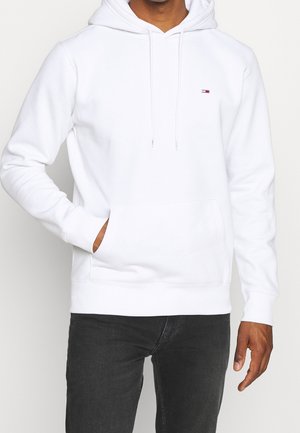 Sweatshirt blanc à capuche avec une poche ventrale, manches longues et logo discret sur la poitrine. Texture de tissu douce et coupe décontractée.