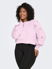 Light pink sweatshirt with puff sleeves featuring floral cut-out patterns, paired with black leggings. Smooth texture and relaxed fit.