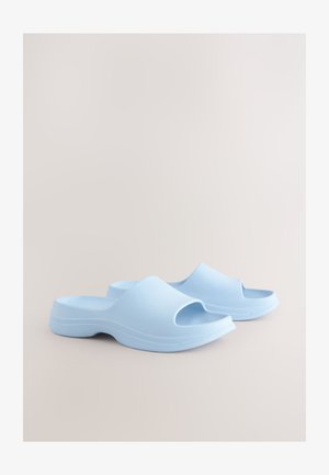 Gaiši zilas ieslīdzamas sandales no gludas plastmasas ar atvērtu pirkstu daļu un konturētu zolīti ar smalkām horizontālām līnijām.