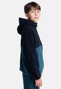 Fleece hoodie die marineblauwe en teal stof combineert, met een capuchon en een half-rits ontwerp. Zachte textuur en een ontspannen pasvorm.