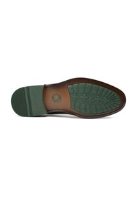 Brown leather shoe sole with a green rubber tread, featuring a circular logo and patterned grip design, smooth texture, and curved shape.