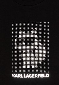 Μαύρο μπλουζάκι με ψηφιακή λευκή γραφική παράσταση ενός καρτούν που φορά γυαλιά ηλίου, με την επιγραφή "KARL LAGERFELD" από κάτω.
