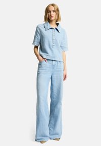 Lyseblå denim skjorte med korte ærmer, lidt løs pasform og knaplukning, parret med en bredbenet lys blå denim jeans.