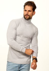 Gray knit turtleneck sweater with fitted long sleeves and a ribbed hem, worn with light blue jeans. Smooth texture, casual fit.