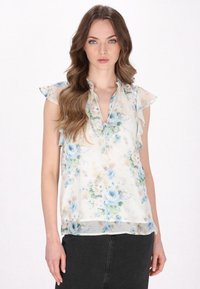 Blumenbluse aus durchsichtiger, leichter Stoffqualität. Mit einem Rüschenausschnitt und Rüschenkanten an den Ärmeln. Heller Cremeton mit blauen und grünen Blumenmustern.