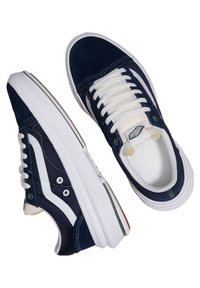 Baskets en suède bleu marine avec lacets blancs, semelles en caoutchouc et rayures blanches sur les côtés. Elles disposent d'œillets ronds et d'un col rembourré.