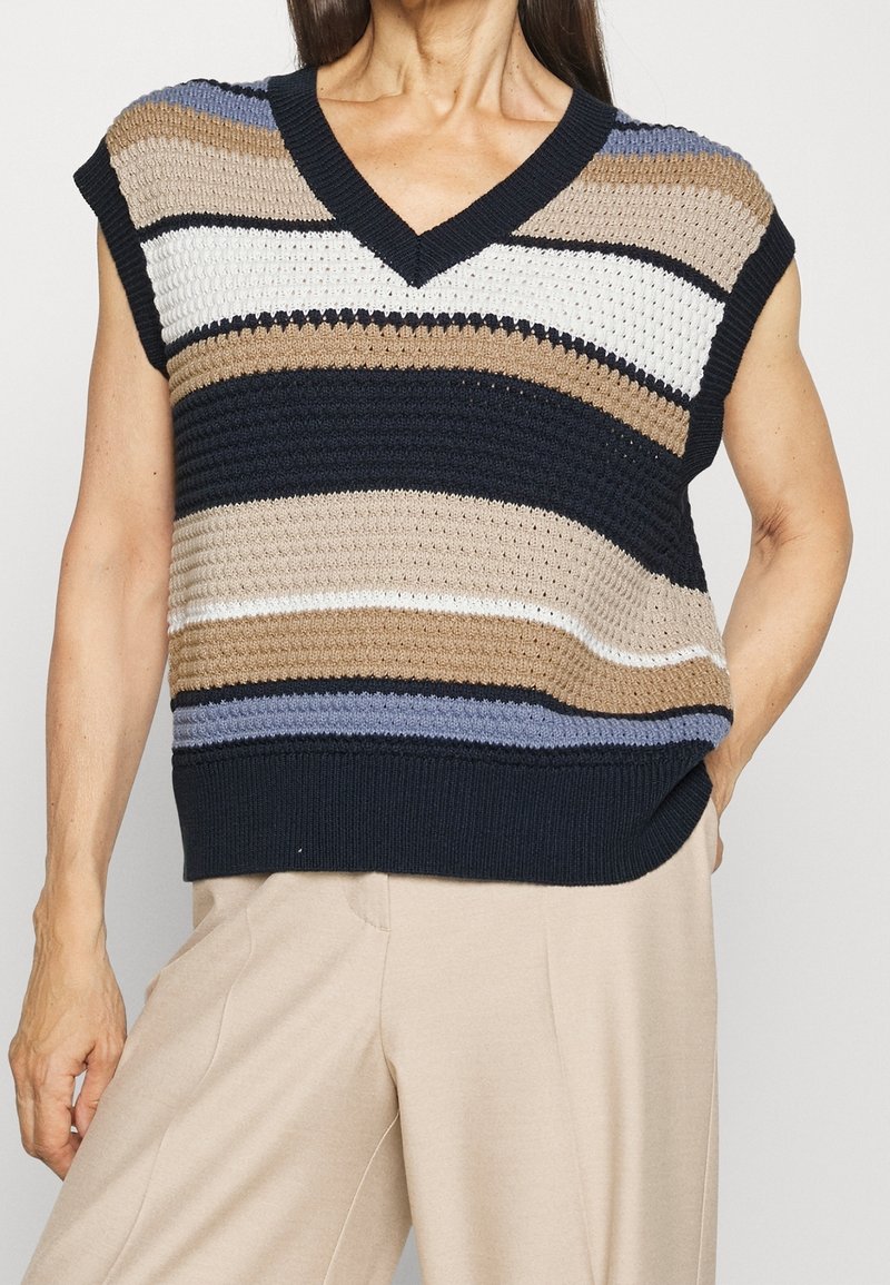 Stickad ärmlös topp med V-ringning, prydd med horisontella ränder i marinblått, beige, vitt och ljusblått. Strukturen är stickad med en ribbad nederkant.