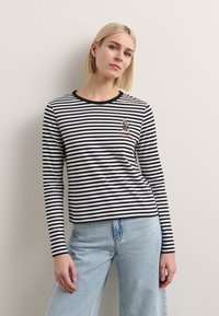Long-sleeve striped shirt in black and white cotton with a round neckline, featuring a cartoon character embroidered on the left chest.