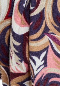 Tela suave con patrones florales abstractos en tonos de púrpura, rosa, beige, blanco y marrón, mostrada en pliegues en primer plano.