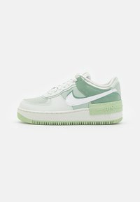 White and light green Nike Air sneakers featuring leather upper, textured accents, thick sole, and visible branding on the heel and side.