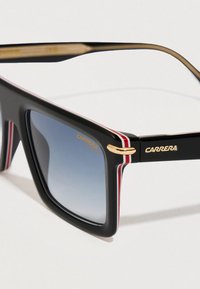 Gafas de sol Carrera con montura de plástico negro, lentes azules degradados, rayas rojas y blancas a los lados, y detalles en dorado.