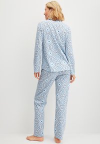 Blauwe pyjama met een geometrisch patroon, lange mouwen en een broek van zacht materiaal, met gedetailleerde bloemmotieven.