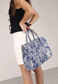 Bolso tote azul con diseño floral, hecho de tela resistente, con dos asas cortas y forma rectangular.