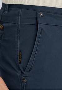 Pantaloni blu navy realizzati in tessuto misto cotone con tasca laterale, chiusura con bottone e etichetta del logo PME Legend sul lato.