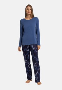 Top azul de manga larga combinado con pantalones oscuros de color marino que presentan un patrón de hojas blancas. Ambos hechos de una tela suave y cómoda.