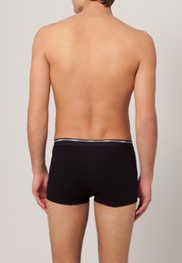 Sorte bomulds boxershorts med en elastisk kant, der viser "Jockey" logoet, tætsiddende design og glat tekstur, set fra bagsiden.