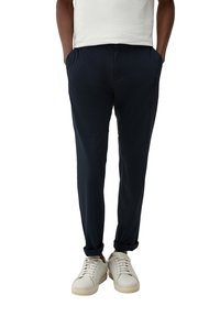 Navyblauwe taps toelopende broek van een zachte stof, met zijzakken, een elastische tailleband en opgerolde manchetten, gecombineerd met witte sneakers.