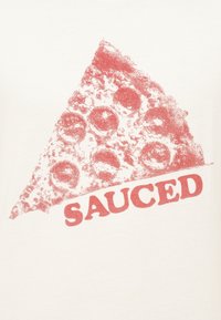 Λευκό μπλουζάκι με κόκκινο γραφικό ενός κομματιού πίτσας με πεπερόνι και τη λέξη "SAUCED" από κάτω, εκτυπωμένη με έντονα γράμματα.
