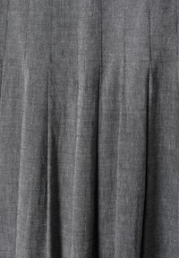 Tessuto di lino grigio con pieghe verticali e una superficie strutturata. Il materiale appare leggero e traspirante, con una lucentezza sottile.