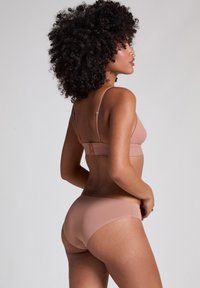 Nude-kleur bikini set met een driehoekige beha met verstelbare bandjes en bijpassende low-rise slipjes, gemaakt van gladde, rekbare stof.