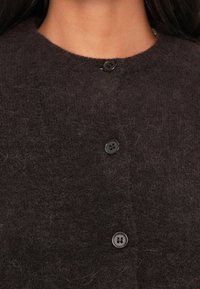 Cardigan di lana scura con colletto rotondo, quattro bottoni neri e una finitura morbida e testurizzata.