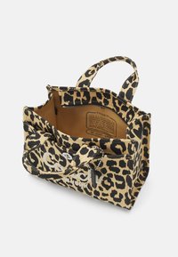 Petit sac cabas ouvert avec imprimé léopard, poignées courtes, poche zippée à l'avant et étiquette en tissu visible à l'intérieur.