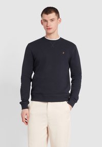 Granatowa bluza crewneck wykonana z bawełny, z prążkowanymi mankietami i dolnym wykończeniem, z małym żółtym logo na piersi i klasycznym krojem.