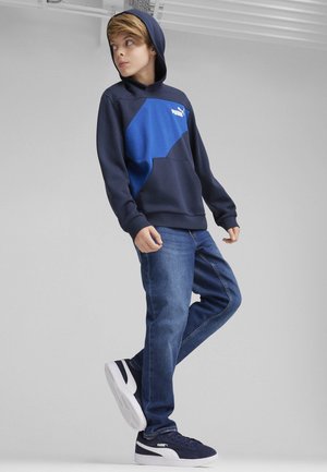 Granatowy hoodie z jasnoniebieskimi akcentami, kieszeń kangurza, logo PUMA, w połączeniu z niebieskimi dżinsami i granatowymi trampkami.